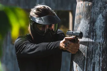 Woman wearing airsoft gear face protection aims and airsoft gun